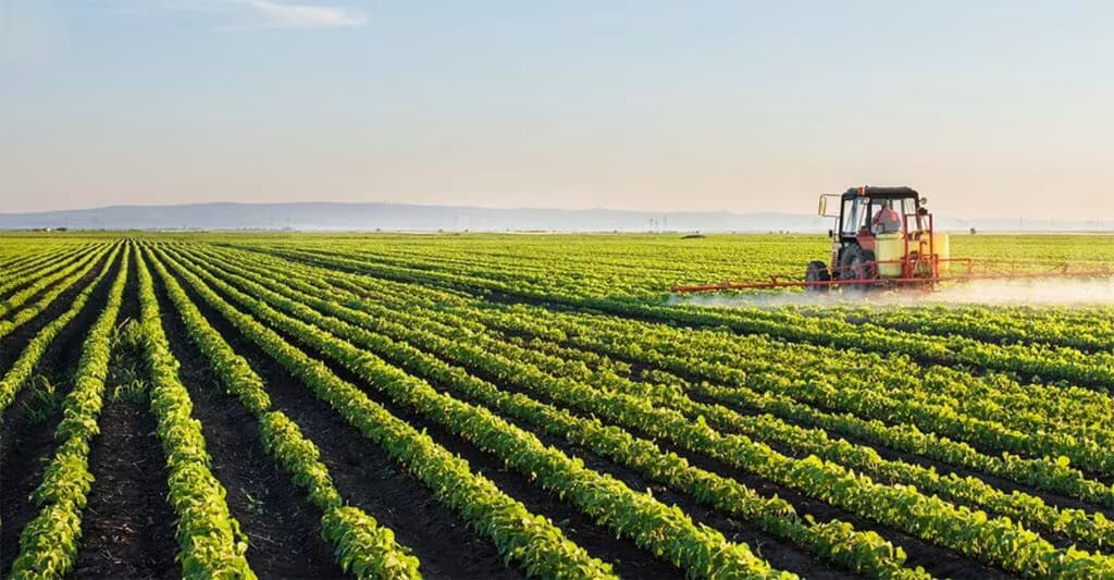 Trator agrícola realizando pulverização em lavoura verde com tecnologia de precisão - crescimento das agritechs e inovação no agronegócio 2026