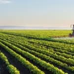 Trator agrícola realizando pulverização em lavoura verde com tecnologia de precisão - crescimento das agritechs e inovação no agronegócio 2026