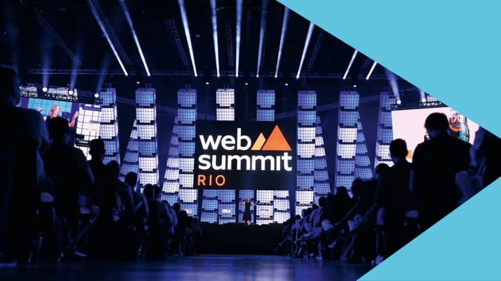Plateia de executivos e diretores no Web Summit Rio, o maior evento de tecnologia e networking da América Latina, com o palco principal ao fundo.